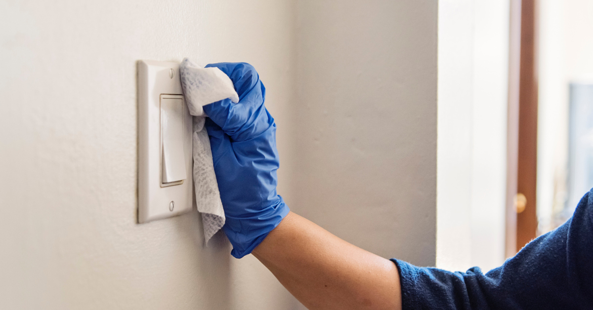 Gloved hand wiping light switch 